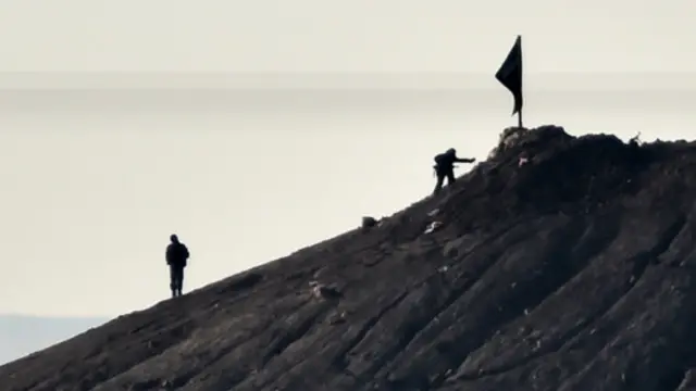 İslam Dövləti qruplaşmasının döyüşçüsü Kobani şəhəri yaxınlığındakı təpənın zirvəsində. 