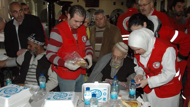 کارکنان هلال احمر سوریه به مردمی که به مناطق تحت کنترل دولت در حمص رسیده‌اند غذا و دارو می‌دهند