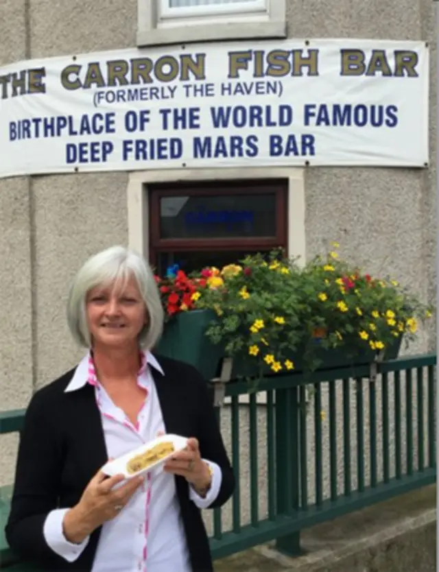 "Carron Fish Barı"-ın sahibi Linda Watson məşhur plakatın qarşısında.