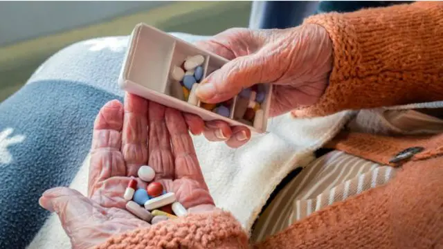 Una persona anciana con medicinas en la mano