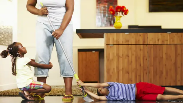 Mujer limpiando el piso y niños a su alrededor