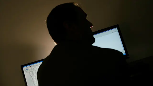 Hombre de espaldas mirando dos pantallas de computadora