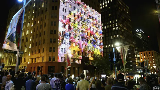 Dalam acara peringatan yang emosional itu, penyelenggara menampilkan proyeksi gambar karangan bunga di bangunan kafe tersebut.
