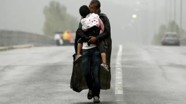 Suriyeli bir mülteci yağmur altında Yunanistan'ın Makedonya sınırına doğru yürürken.