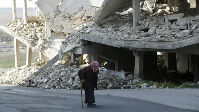 一位老人在伊德利卜一座被炸毁的建筑前走过