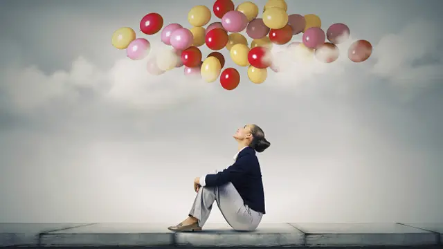 Женщина мечтательно смотрит на разноцветные шары