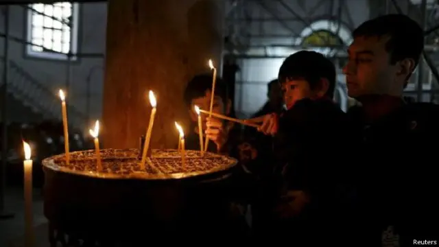 متعبدون يوقدون الشموع داخل كنيسة أثرية يرجع تاريخها إلى 1600 عام