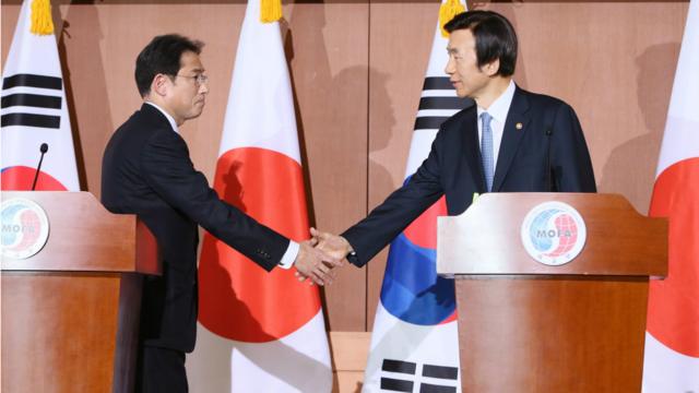 日本外相岸田文雄（左）與韓國外長尹炳世（右）在28日的聯合記者會上握手。