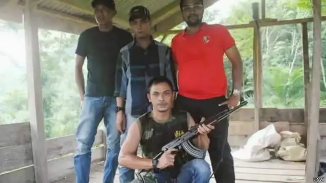 Din Minimi (tengah duduk) memegang senjata.