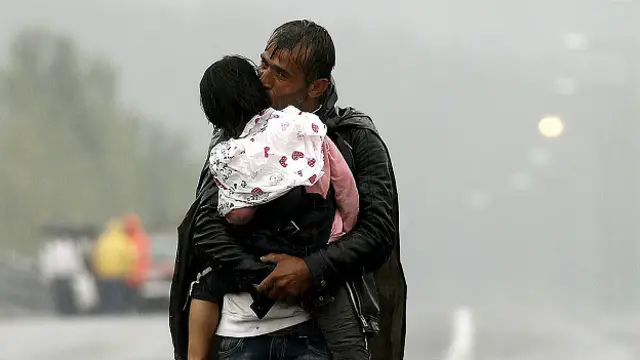 Yunanistan Makedonya sınırını çocuğuyla birlikte geçen Suriyeli bir mülteci.