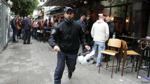 شرطي اسرائيلي يهرول ويظهر خلفه مكان حادث اطلاق النار في 1 يناير/ كانون الثاني