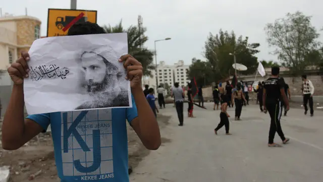 متظاهرون يرفعون صورة النمر، في البحرين، احتجاجا على إعدامه
