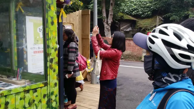 一名女子照相记录悼念“大橘子”的黄丝带(BBC中文网图片4/1/2016)