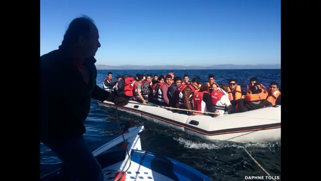 Рыбак тащит на буксире лодку с мигрантами