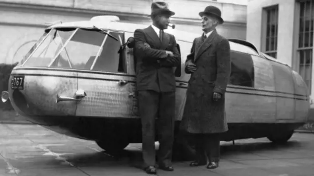 1933年11月：飞行家及潜水家阿尔·威廉姆斯（Al Williams）上尉与时任美国总统罗斯福的私人秘书马文·麦金泰尔（Marvin McIntyre）站在Dymaxion概念车前。(Underwood Archives/Getty Images)