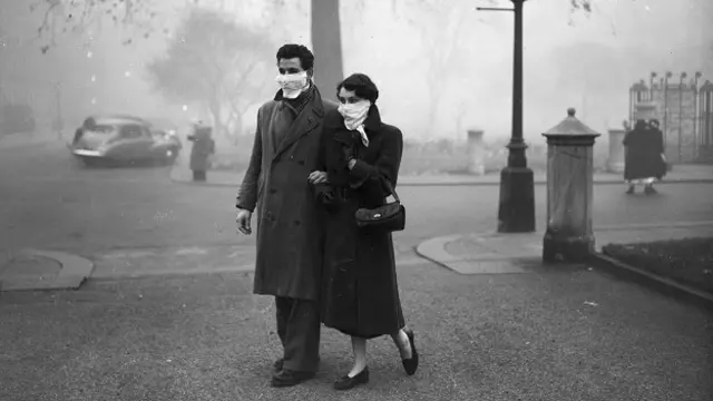 Пара на улицах Лондона, ноябрь 1953 года. Спустя почти год после Великого смога лондонцам все еще нужны были фильтрующие маски