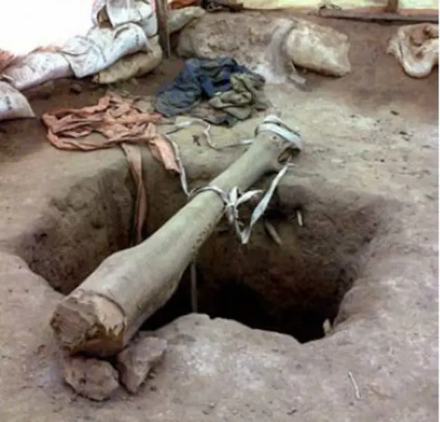 Des mineurs descendent dans des puits de mine grâce à une corde attachée à une poutre tendue au-dessus de la fosse.