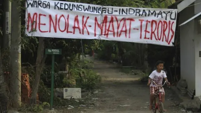 Warga yang sempat menolak jenazah Azan, membentangkan spanduk penentangan mereka. 