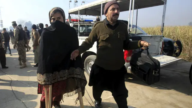 حملے کے بعد ایک ٹیچر کو یونیورسٹی سے باہر لے جایا جا رہا ہے