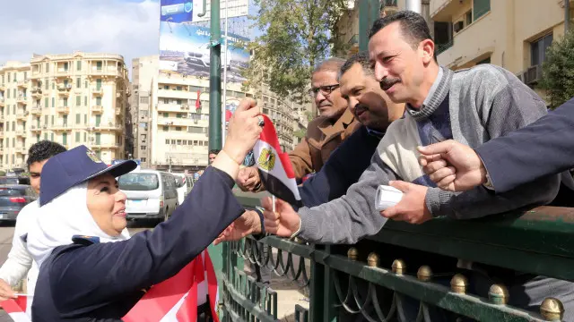 ضابطة شرطة توزع الإعلام على مواطنين في ميدان التحرير.