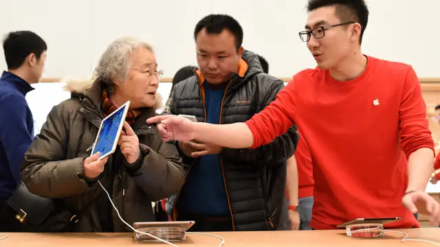 遼寧瀋陽萬象城蘋果零售店內一名老太太(左)在品詳一台iPad(新華社圖片9/1/2016)