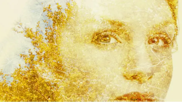 El rostro de una mujer confundido con las hojas de un árbol en otoño