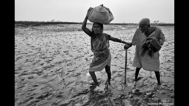 Qadın kişiyə çayı keçməyə kömək edir. Joydeep Mukherjee