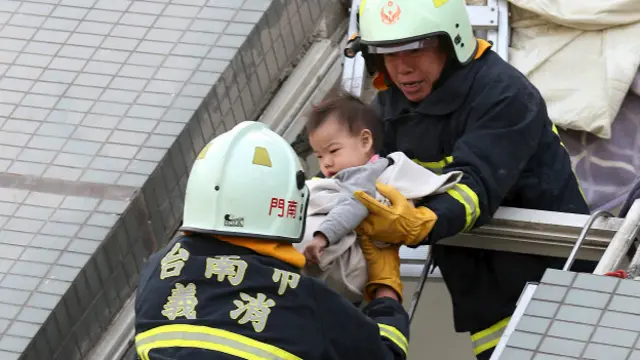 इमारत के मलबे से एक बच्चे को निकालते राहत और बचावकर्मी.