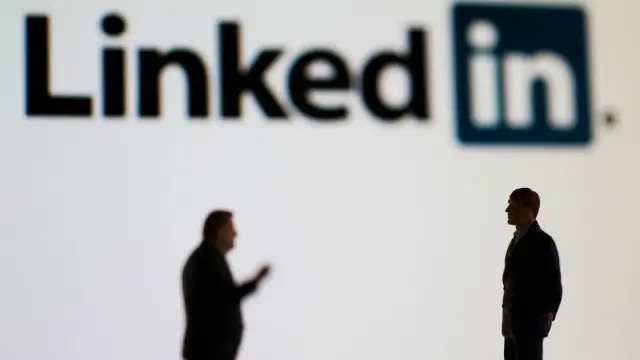 Dos personas hablando. Al fondo, el logotipo de LinkedIn