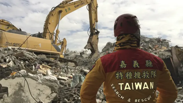 一名救援人員站在倒塌的維冠金龍大樓廢墟上。維冠金龍大樓的倒塌導致重大傷亡，開發商已接受司法調查。