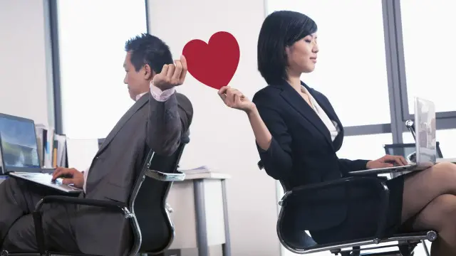 Dos personas pasándose un corazón de papel