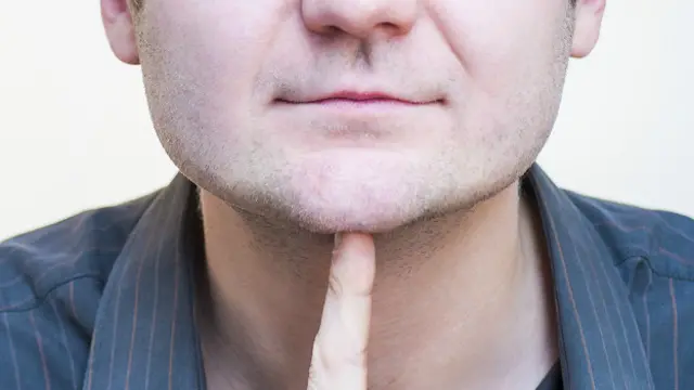 Мужчина указывает пальцем на свой подбородок