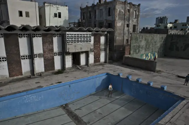 Una mujer posa en vestido de baño dentro de una piscina vacía y abandonada