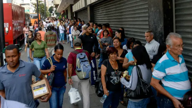 Los venezolanos hacen largas filas fuera de los supermercados para conseguir aliementos.