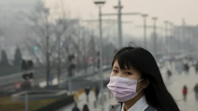 北京街头一名女学生戴着口罩走过（19/12/2015）
