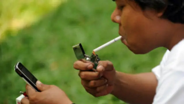 Persona fumando y viendo el teléfono