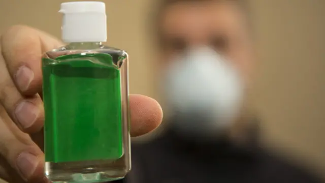 Un hombre sujeta un envase de gel anti bacterial