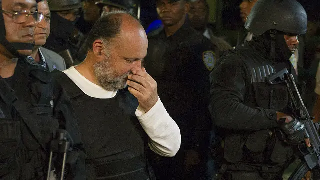 اصطحبت قوات الأمن نودين (وسط) لدى وصوله إلى المطار