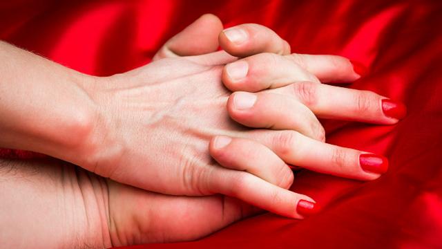Мужская и женская руки на красной простыне