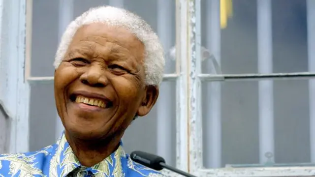 Ông Nelson Mandela đứng trước phòng giam nhà tù trước đây của ông ở đảo Robben năm 2003 (Ảnh: Getty Images)