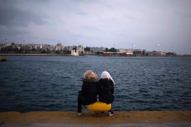 لاجئتان سوريتان تجلسان على الشاطئ في ميناء بيروس في العاصمة اليونانية أثينا، انتظارا لفرصة الهجرة النهائية إلى شمال أوروبا.