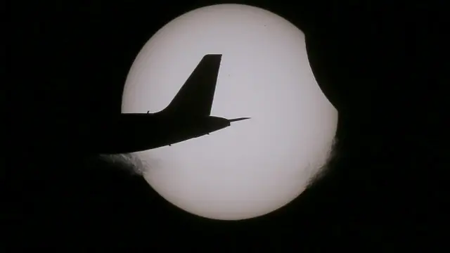 पूर्ण सूर्य ग्रहण के दौरान गुजरता एअर एशिया का एक विमान.