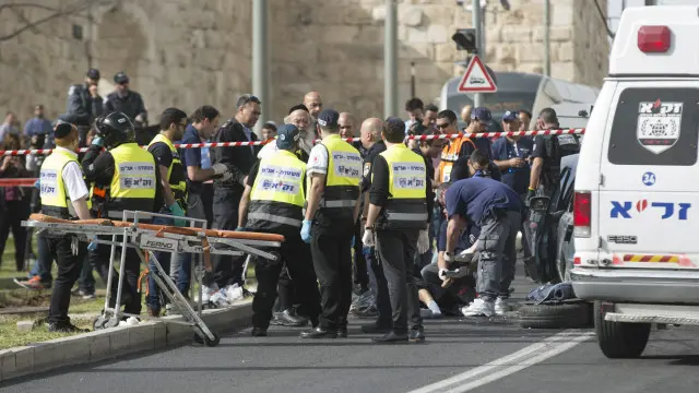 أفراد الشرطة يفحصون جثة أحد الفلسطينيين اللذين قتلا