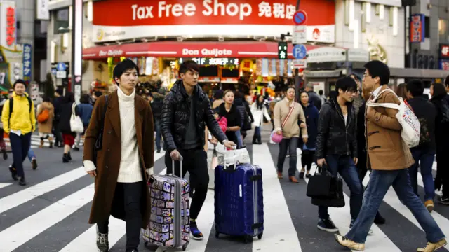 一名旅客拖著行李箱走過東京一家免稅店（11/2/2016）