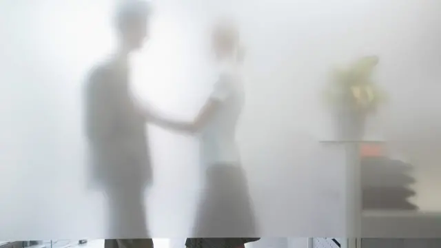 Dos personas en actitud romántica tras una pared de vidrio