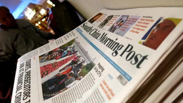 一名媒體記者在香港尖沙咀南華早報集團股東會門外派發的當天《南華早報》(BBC中文網圖片14/3/2016)