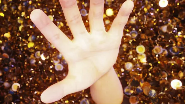 Una mano que sale de un montón de monedas