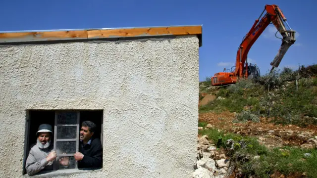 بولدوزر اسرائیلی در حال کندن درخت زیتون مزرعه فلسطینی