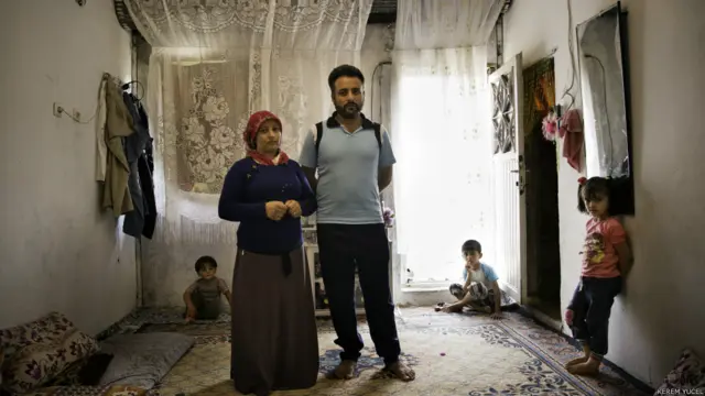 "Tenekeden kepenkleri olan bir depo burası. İçinde tuvaleti bile yok. Gidecek yerimiz yok. Suriye'ye dönmek de istemiyoruz. Karım bir perde buldu. İlk onu astık. Halılar ve ayna. Şimdi daha sıcak. Suriye'deki gibi değil evimiz ama Allah büyük. Zamanla biz de bir yuva kuracağız."