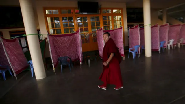 印度达兰萨拉楚拉康寺内一名藏族僧人走过大选投票间（19/3/2016）